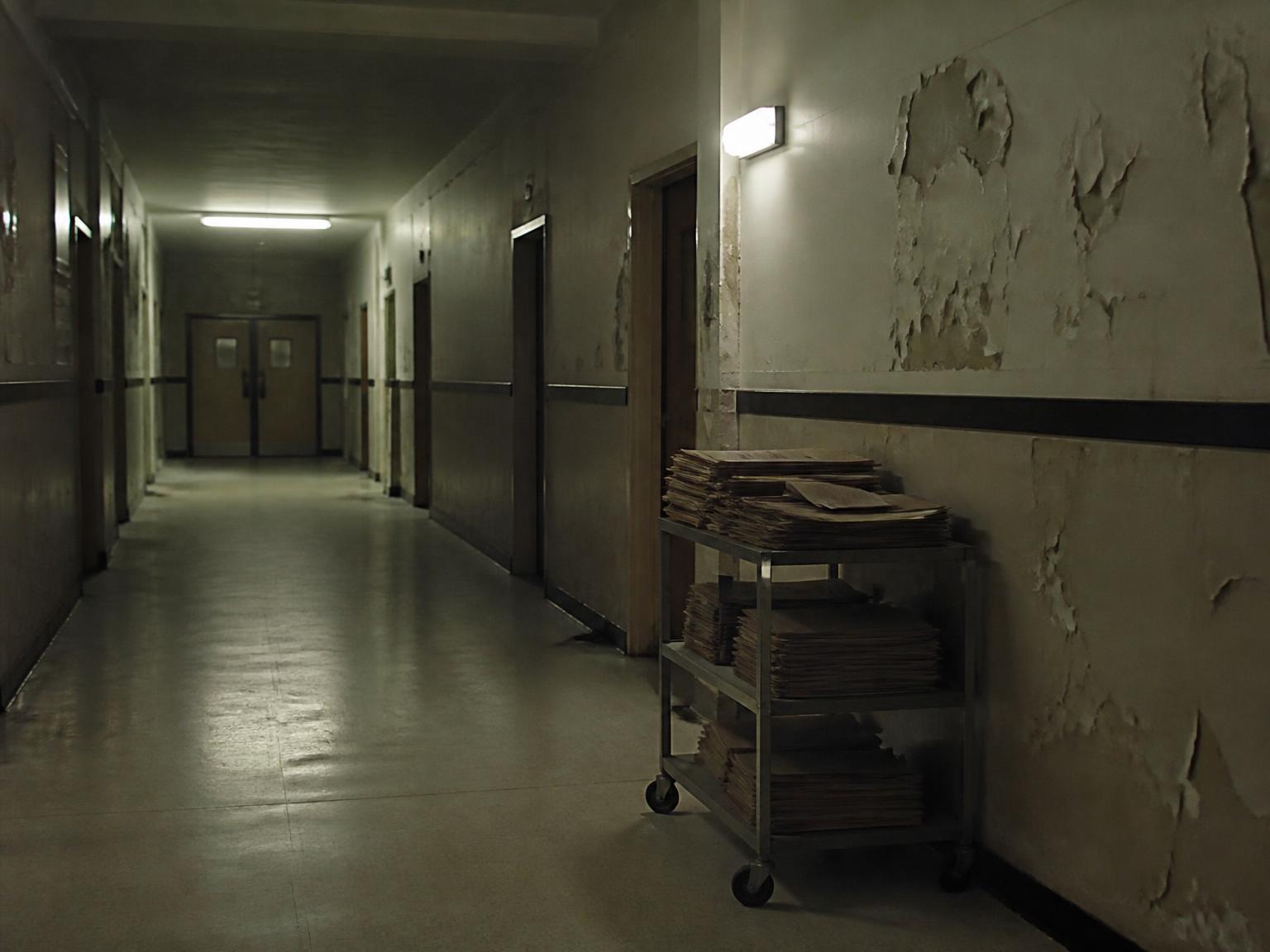 A deserted hospital corridor with an abandoned records trolley